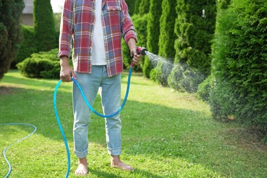 Photo of Man watering lawn with hose in backyard, closeup