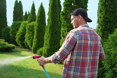 Photo of Man watering lawn with hose in backyard