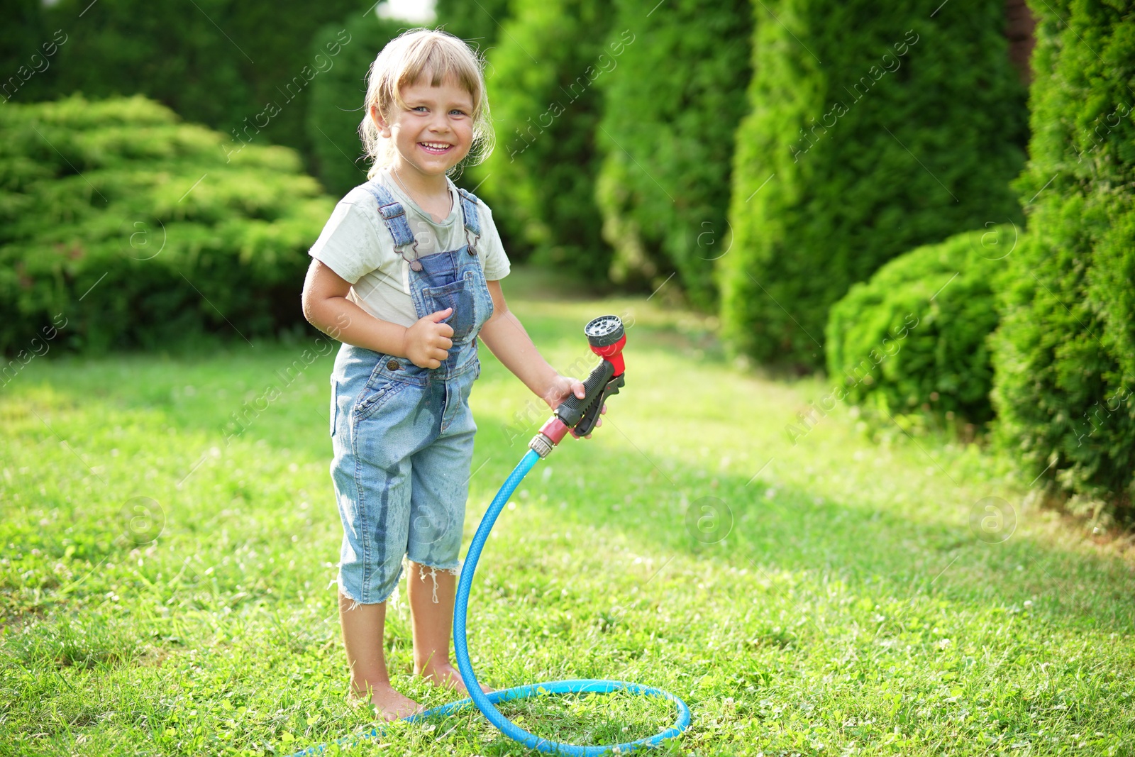 Photo of Little girl with hose in backyard, space for text