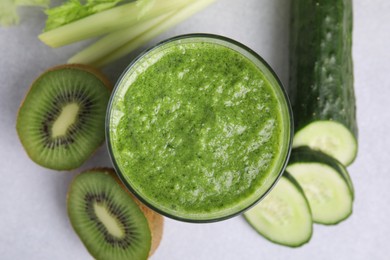 Photo of Delicious green smoothie and ingredients on light table, top view