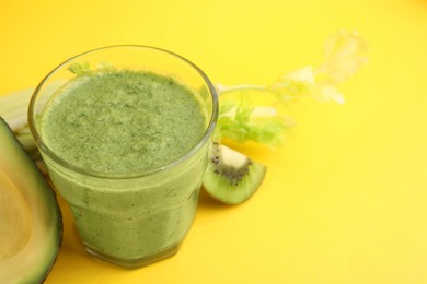 Photo of Delicious green smoothie and ingredients on yellow table, closeup. Space for text