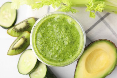 Photo of Delicious green smoothie and ingredients on white table, top view