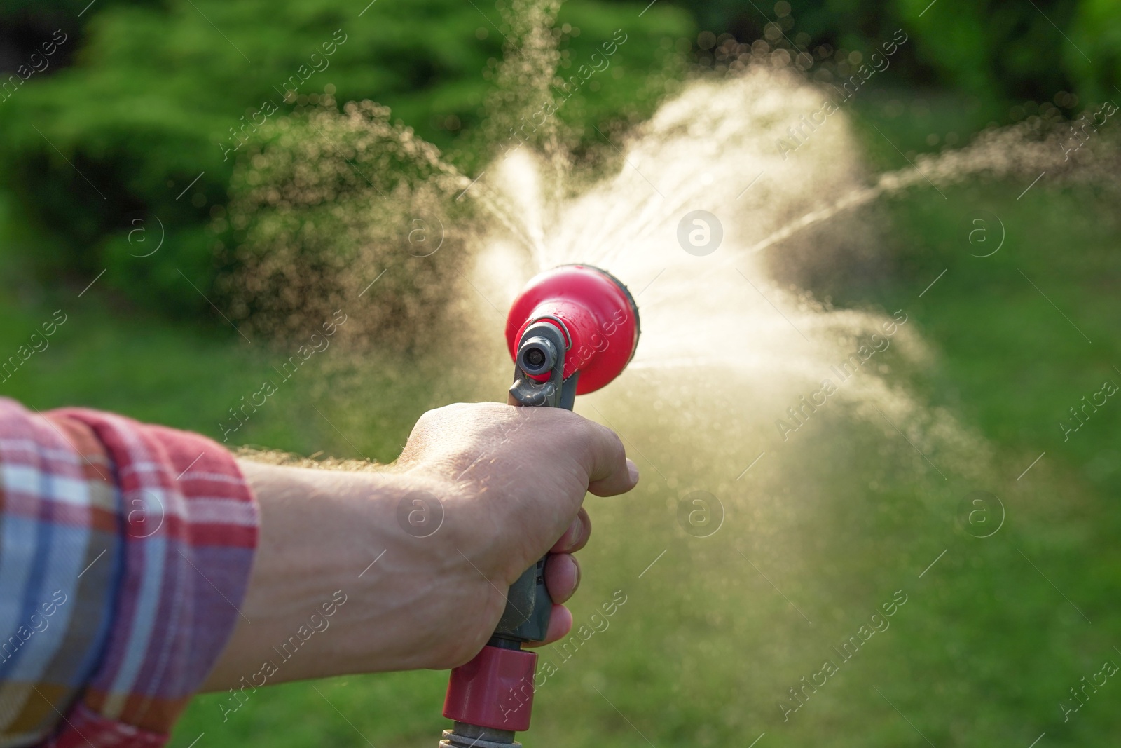 Photo of Man watering lawn with hose in backyard, closeup