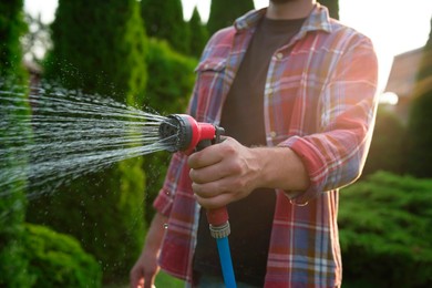 Man watering lawn with hose in backyard, closeup