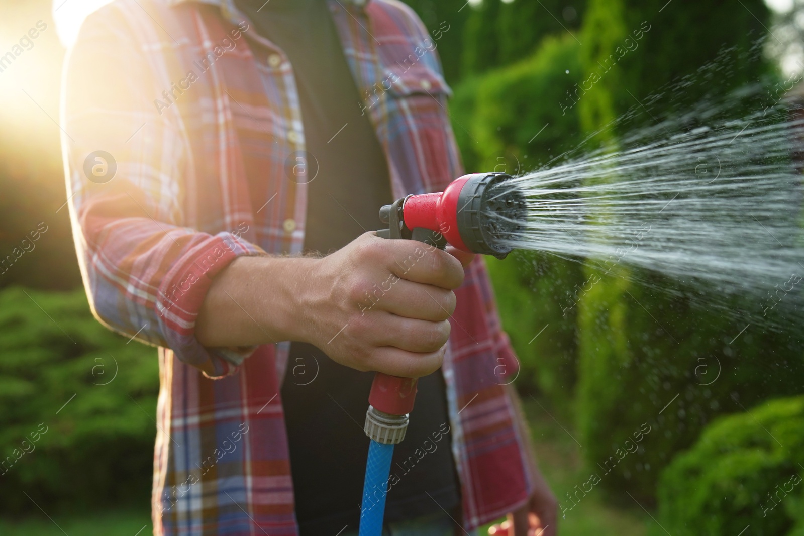 Photo of Man watering lawn with hose in backyard, closeup