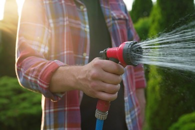 Man watering lawn with hose in backyard, closeup