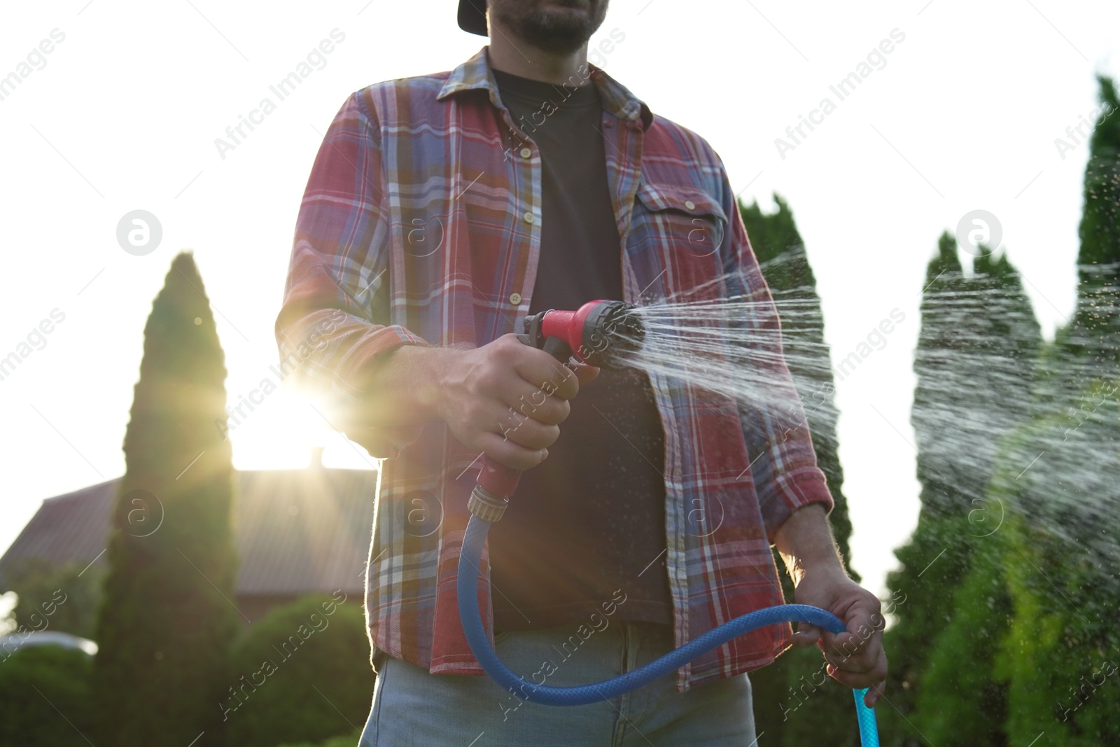 Photo of Man watering lawn with hose in backyard, closeup