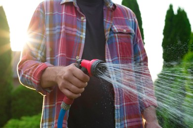 Man watering lawn with hose in backyard, closeup