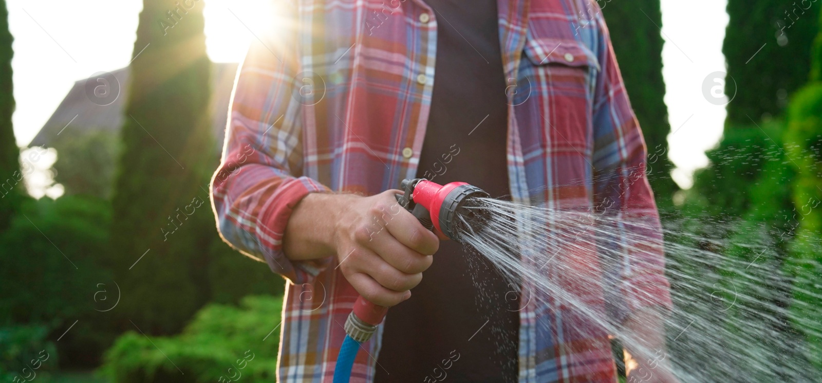 Photo of Man watering lawn with hose in backyard, closeup