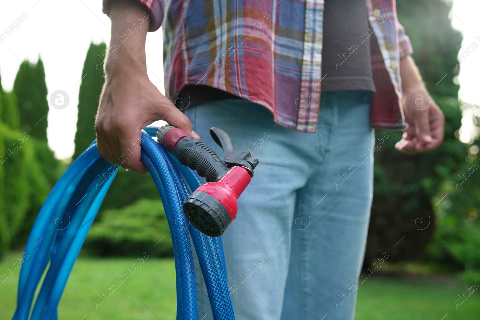 Photo of Man holding watering hose with sprinkler in garden, closeup