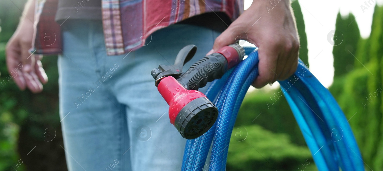 Photo of Man holding watering hose with sprinkler in garden, closeup