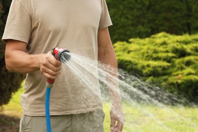 Photo of Man watering lawn with hose in backyard, closeup