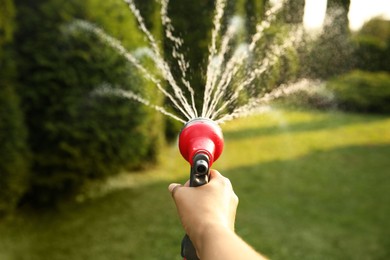 Man watering lawn with hose in backyard, closeup