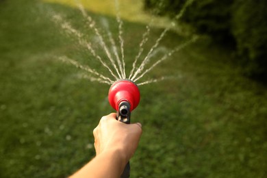 Photo of Man watering lawn with hose in backyard, closeup