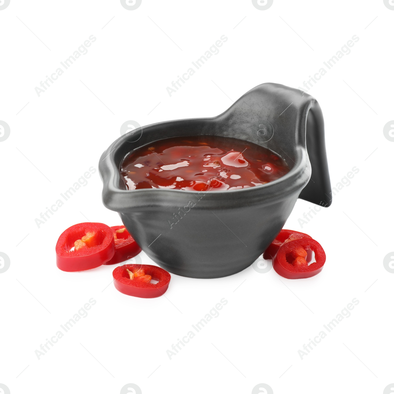 Photo of Hot chili sauce in gravy boat and pepper isolated on white