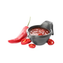 Photo of Hot chili sauce in gravy boat and pepper isolated on white