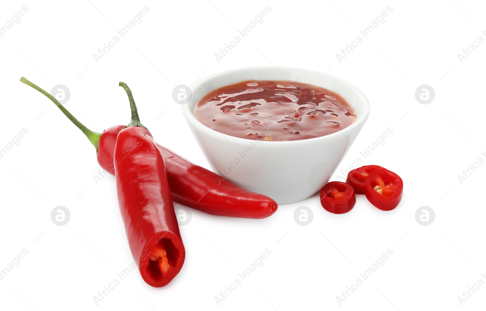 Photo of Hot chili sauce in bowl and peppers isolated on white