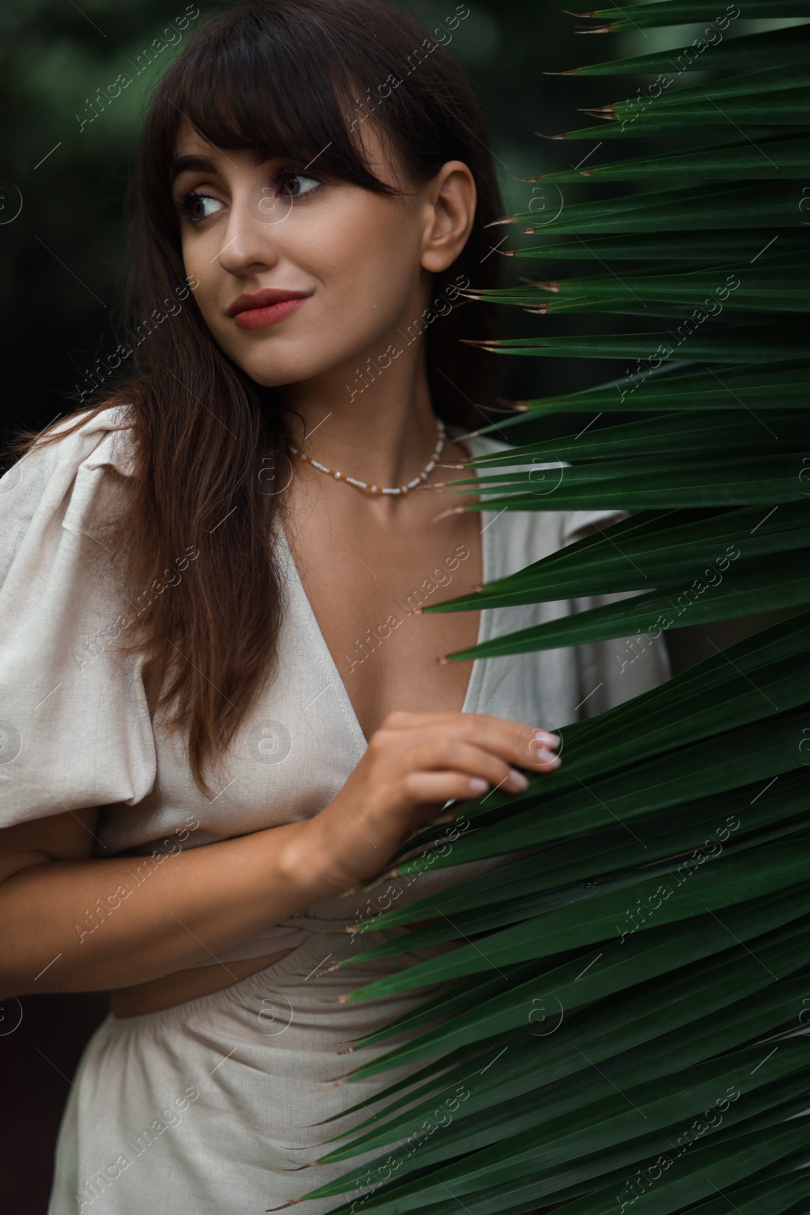 Photo of Portrait of beautiful woman with palm tree leaf outdoors