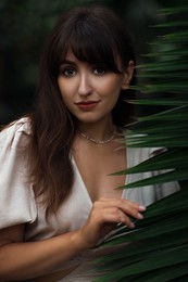 Photo of Portrait of beautiful woman with palm tree leaf outdoors