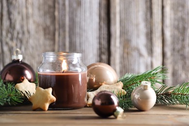 Photo of Burning candle, baubles, cookies and fir branches on wooden table. Christmas atmosphere