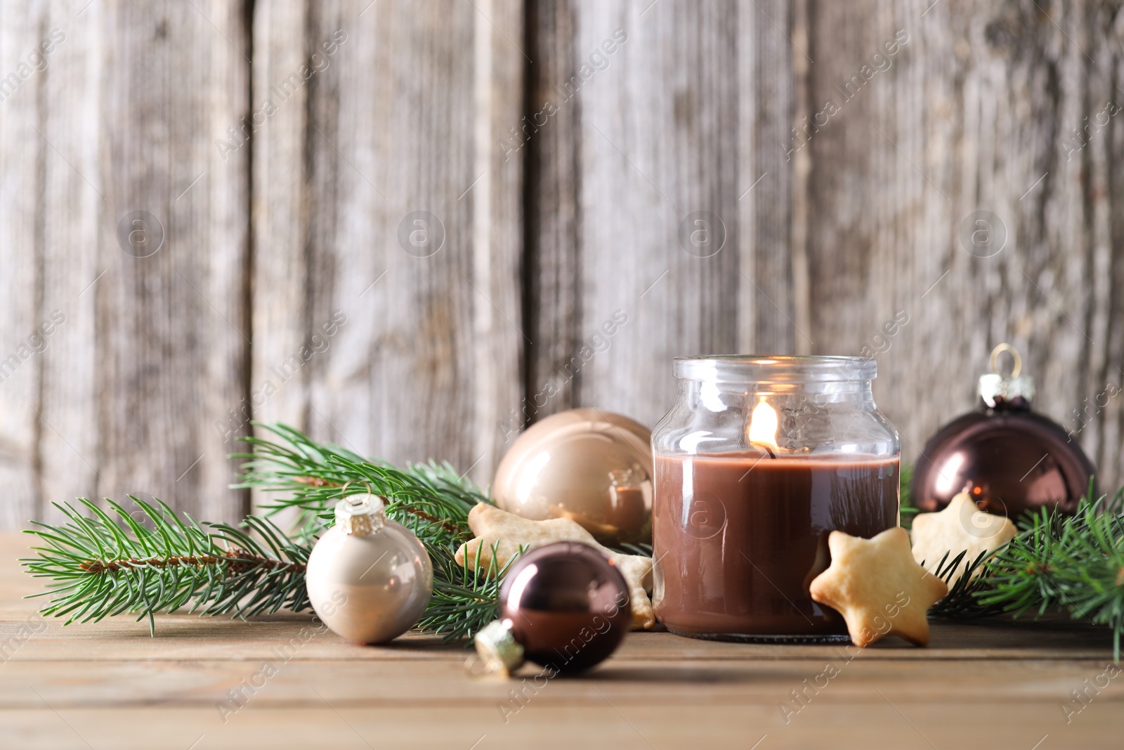 Photo of Burning candle, baubles, cookies and fir branches on wooden table. Space for text