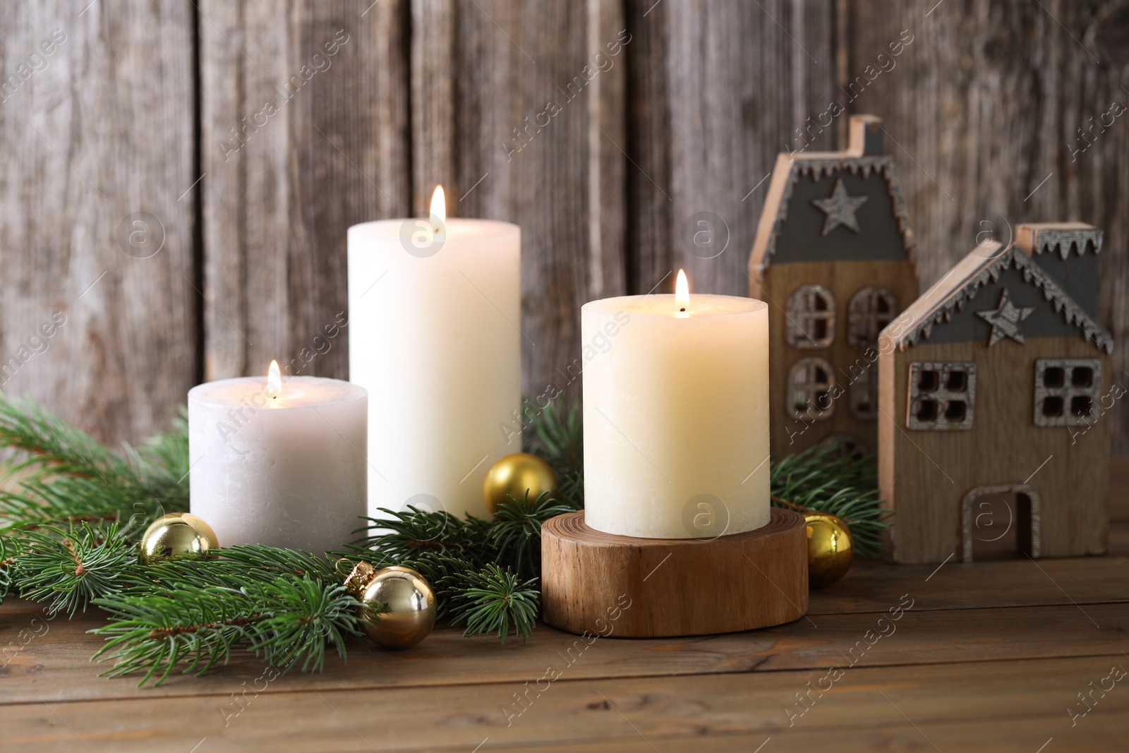 Photo of Burning candles, baubles, fir branches and other Christmas decor on wooden table