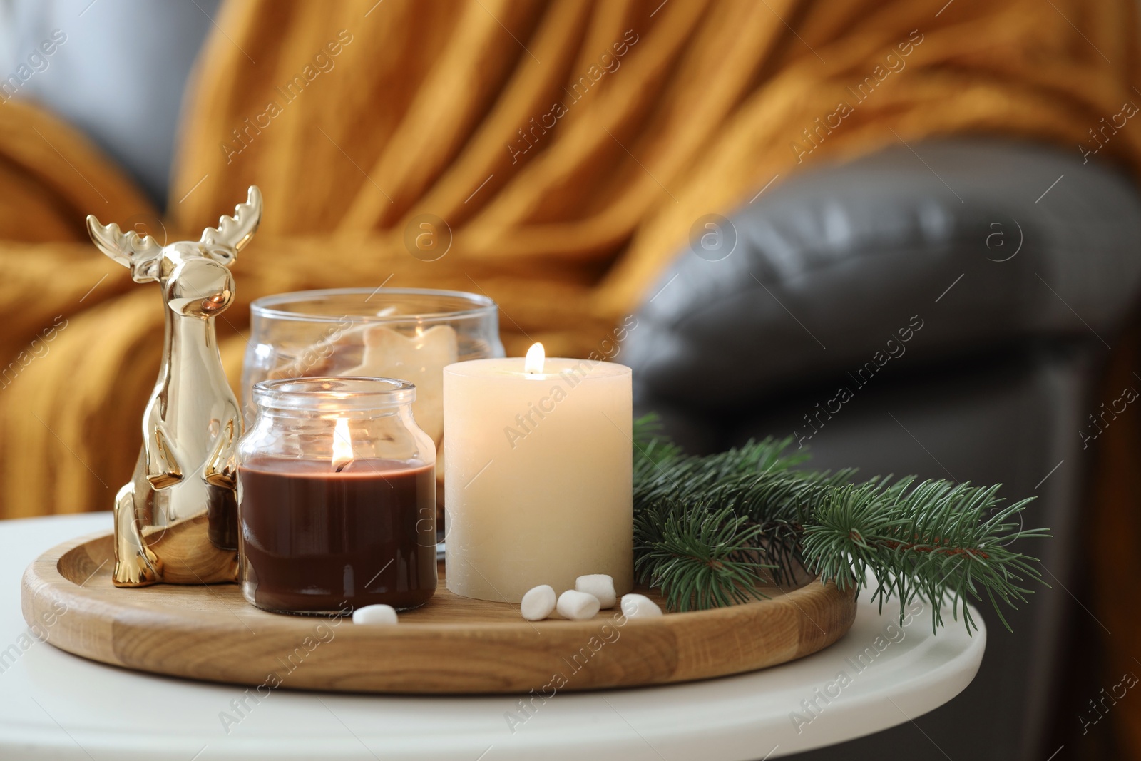 Photo of Burning candles, fir branches and decorative deer on coffee table indoors, space for text. Christmas atmosphere