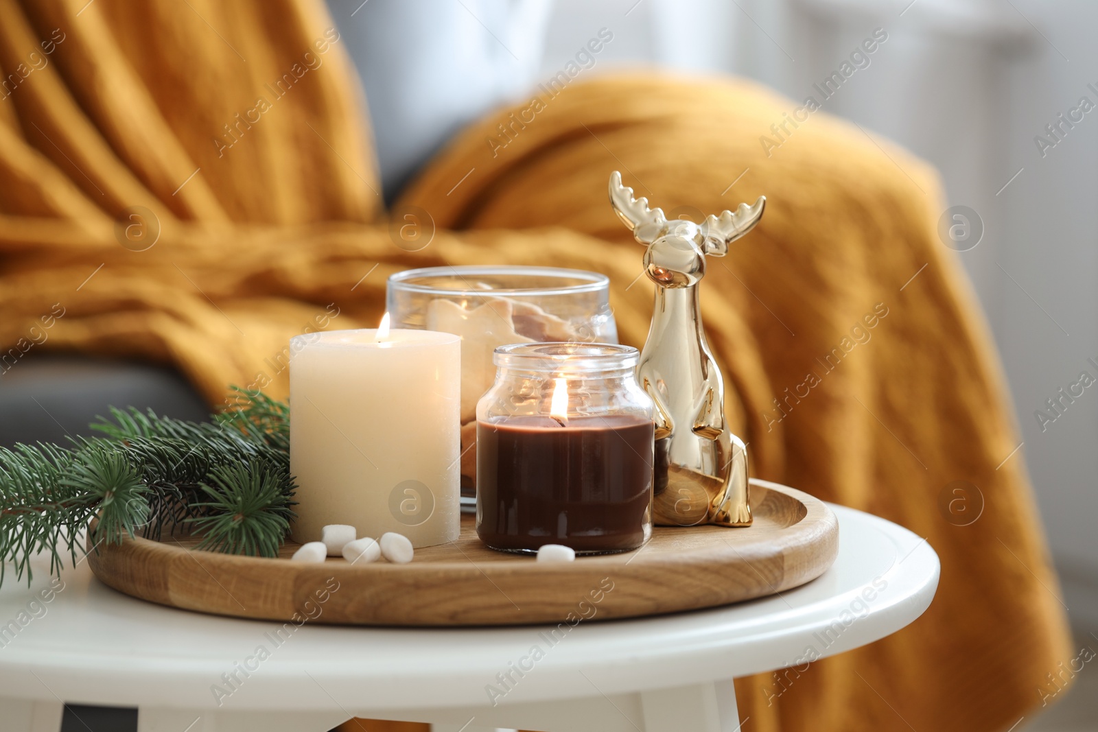 Photo of Burning candles, fir branches and decorative deer on coffee table indoors. Christmas atmosphere