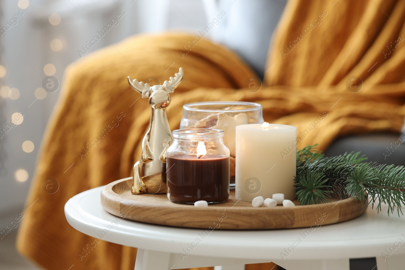 Photo of Burning candles, fir branches and decorative deer on coffee table indoors. Christmas atmosphere