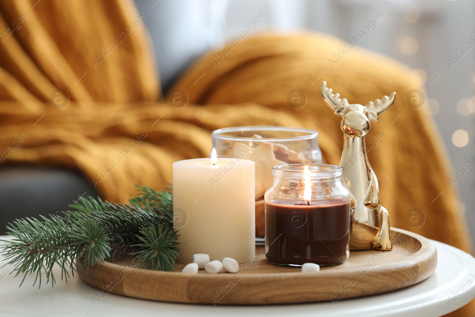 Photo of Burning candles, fir branches and decorative deer on coffee table indoors. Christmas atmosphere