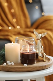 Photo of Burning candles, fir branches and decorative deer on coffee table indoors. Christmas atmosphere