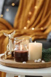 Photo of Burning candles, fir branches and decorative deer on coffee table indoors. Christmas atmosphere