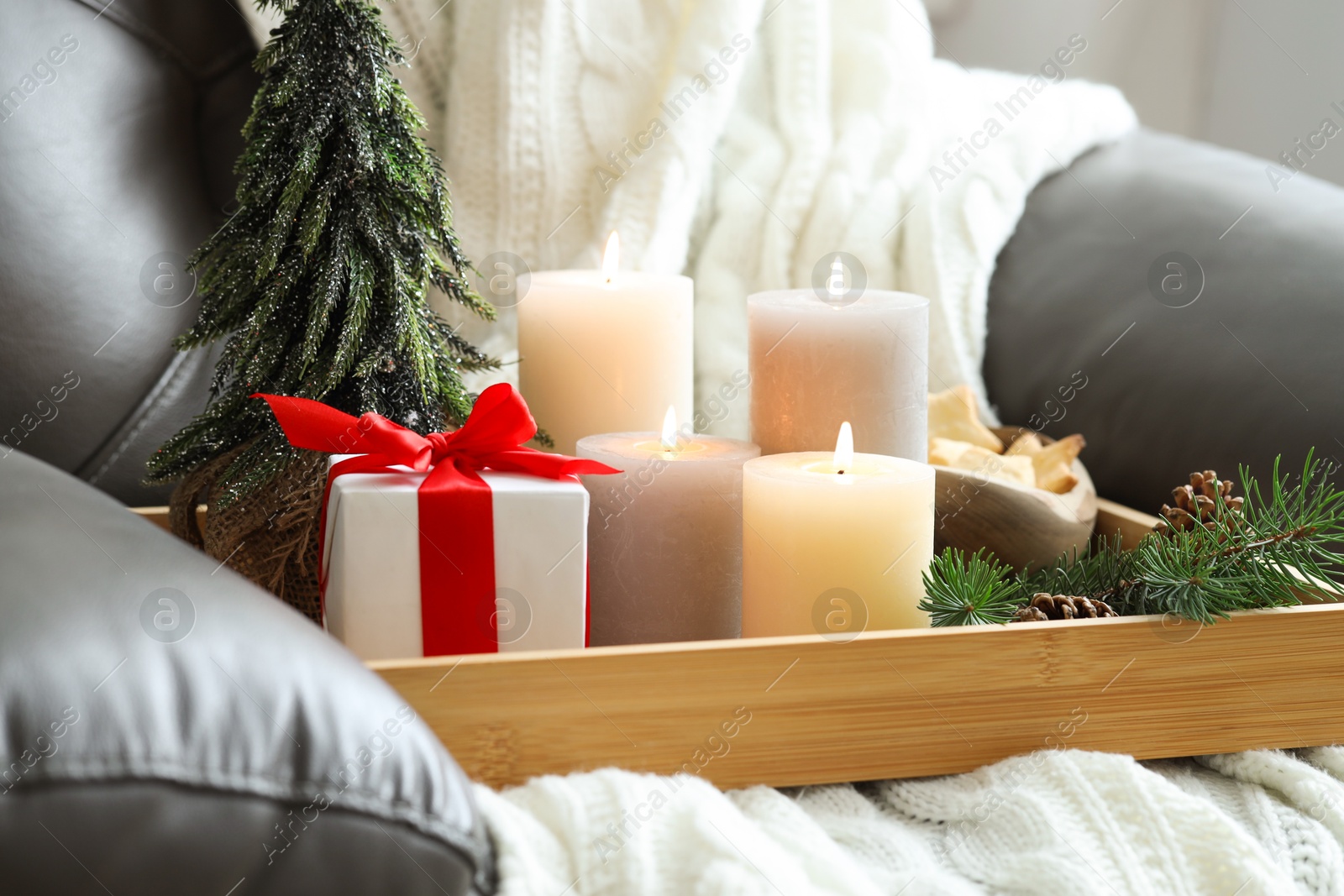 Photo of Tray with burning candles and Christmas decor on armchair