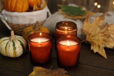 Photo of Burning candles and autumn decor on wooden table