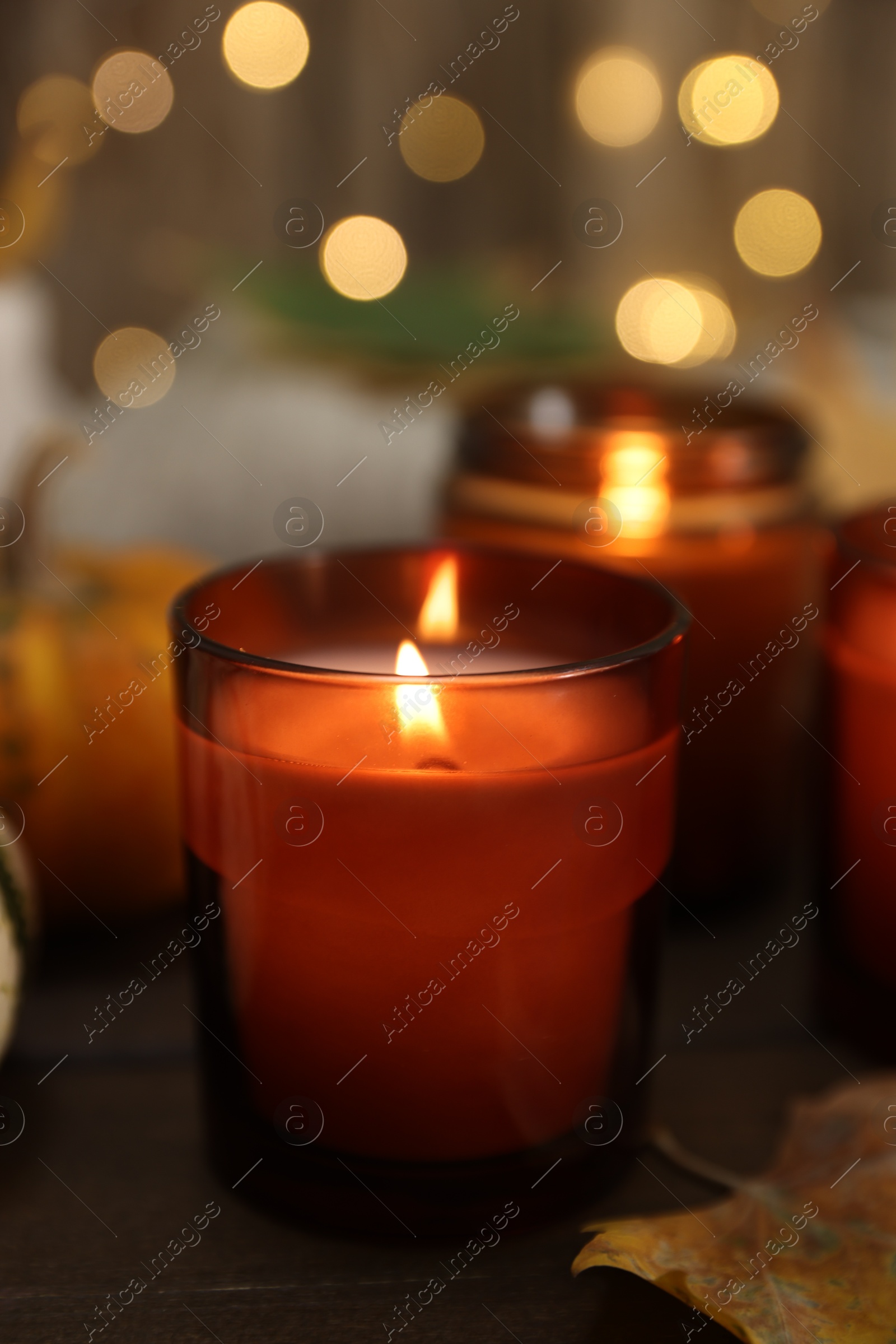 Photo of Burning candle and autumn decor on wooden table, closeup