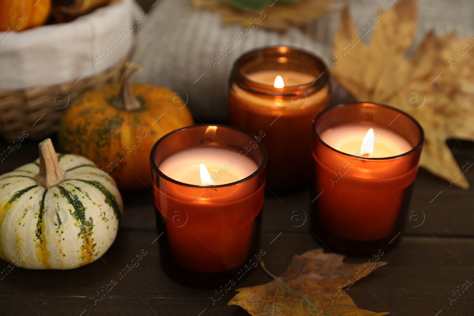 Photo of Burning candles and autumn decor on wooden table, closeup