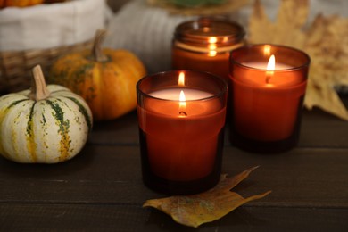 Photo of Burning candles and autumn decor on wooden table, closeup