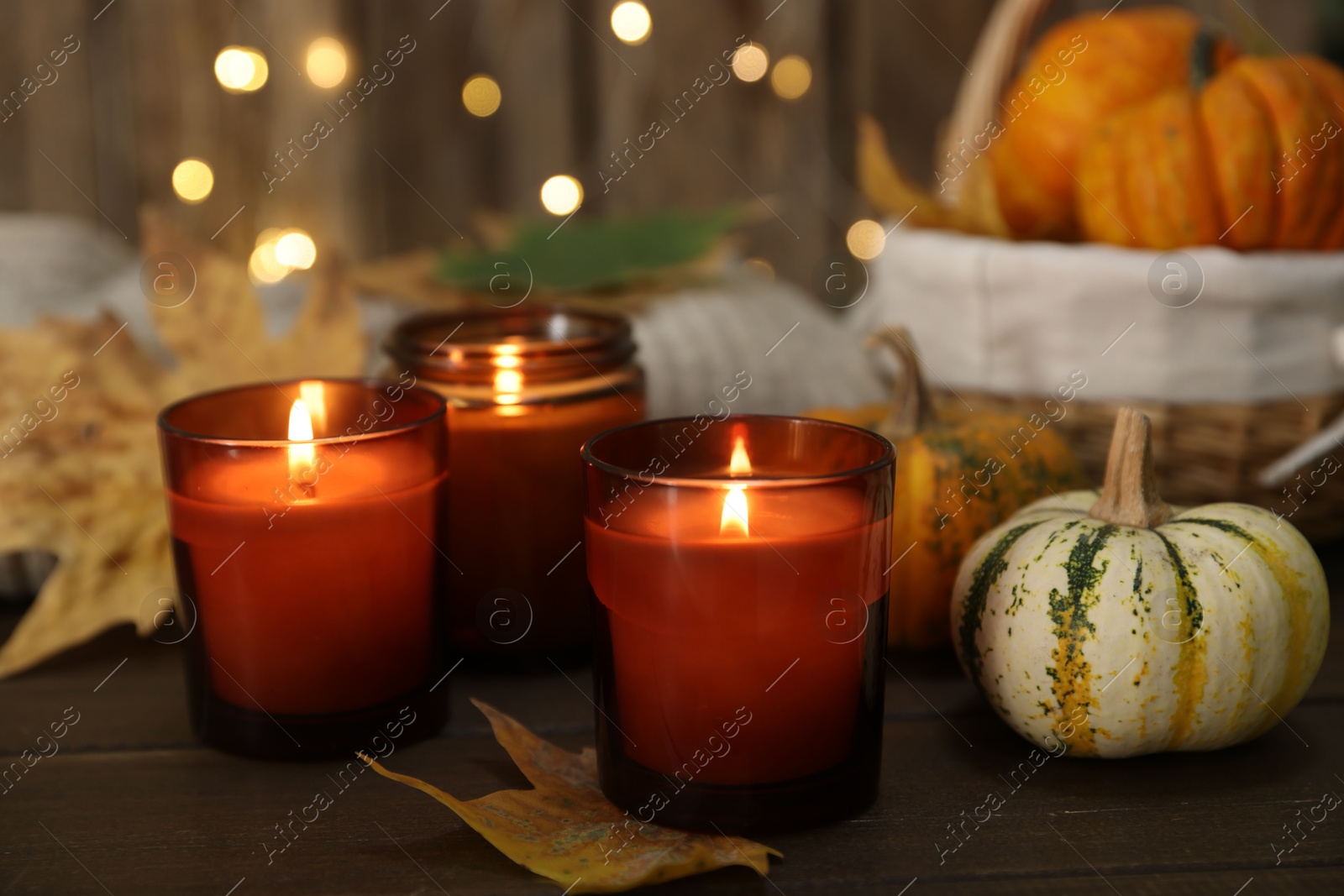 Photo of Burning candles and autumn decor on wooden table