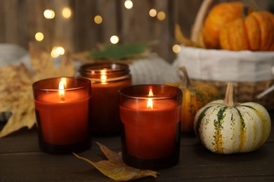 Photo of Burning candles and autumn decor on wooden table