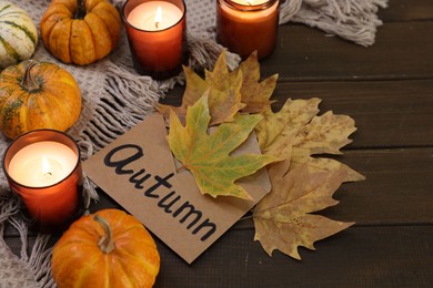 Photo of Envelope with word Autumn, burning candles, dry leaves and pumpkins on wooden table