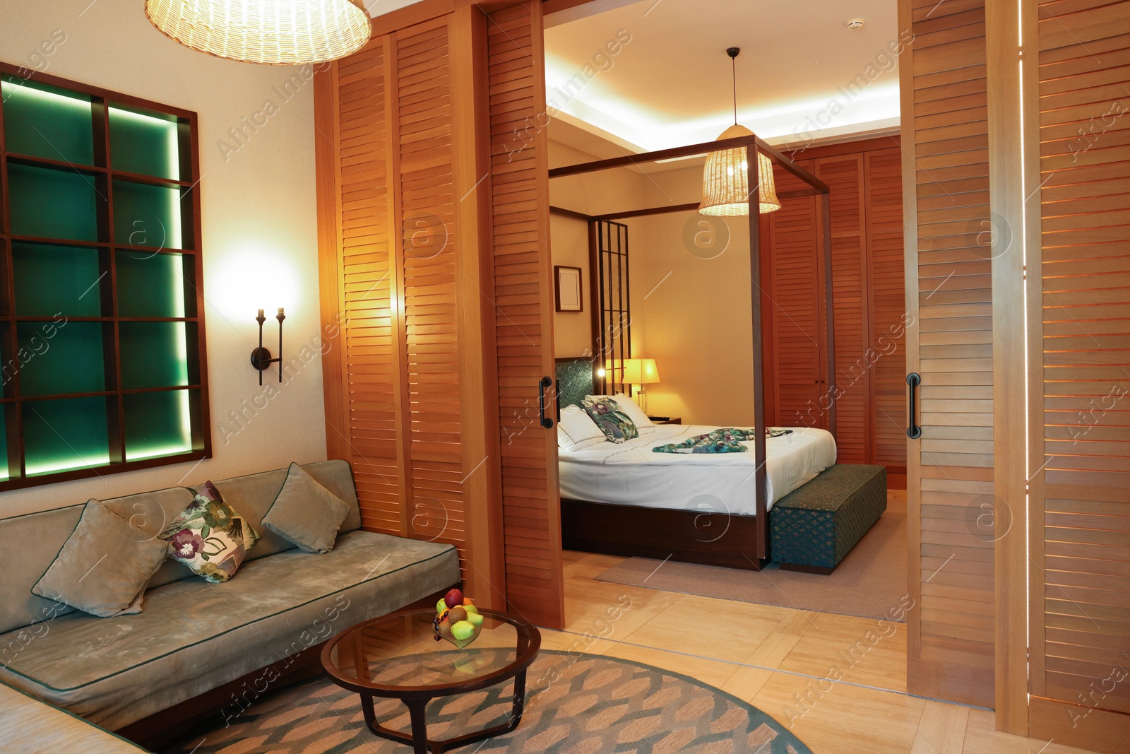 Photo of Stylish hotel room interior with gray sofa, large bed and sliding wooden doors