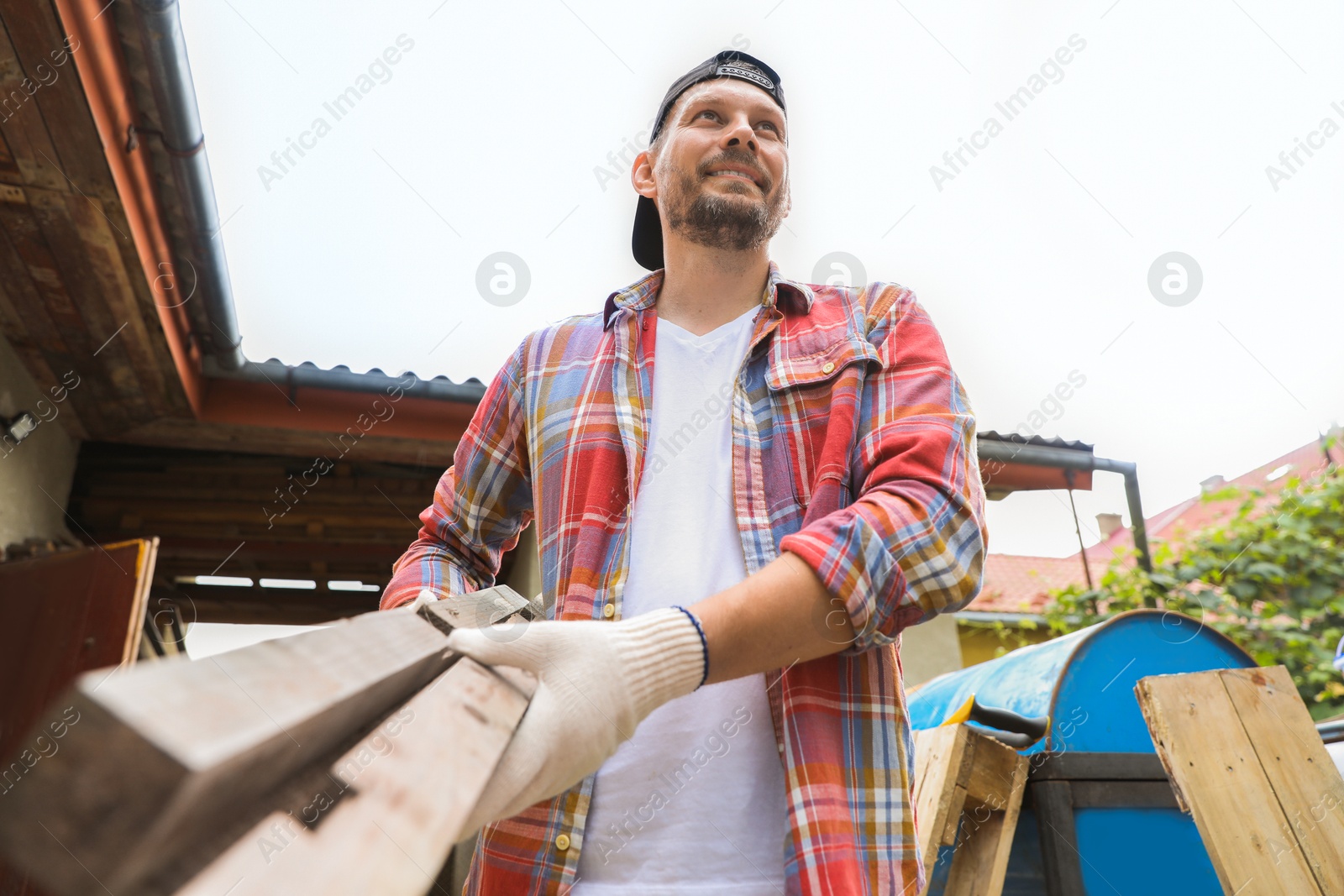 Photo of Man with wooden planks in backyard, low angle view