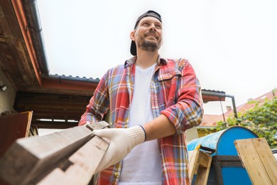 Man with wooden planks in backyard, low angle view