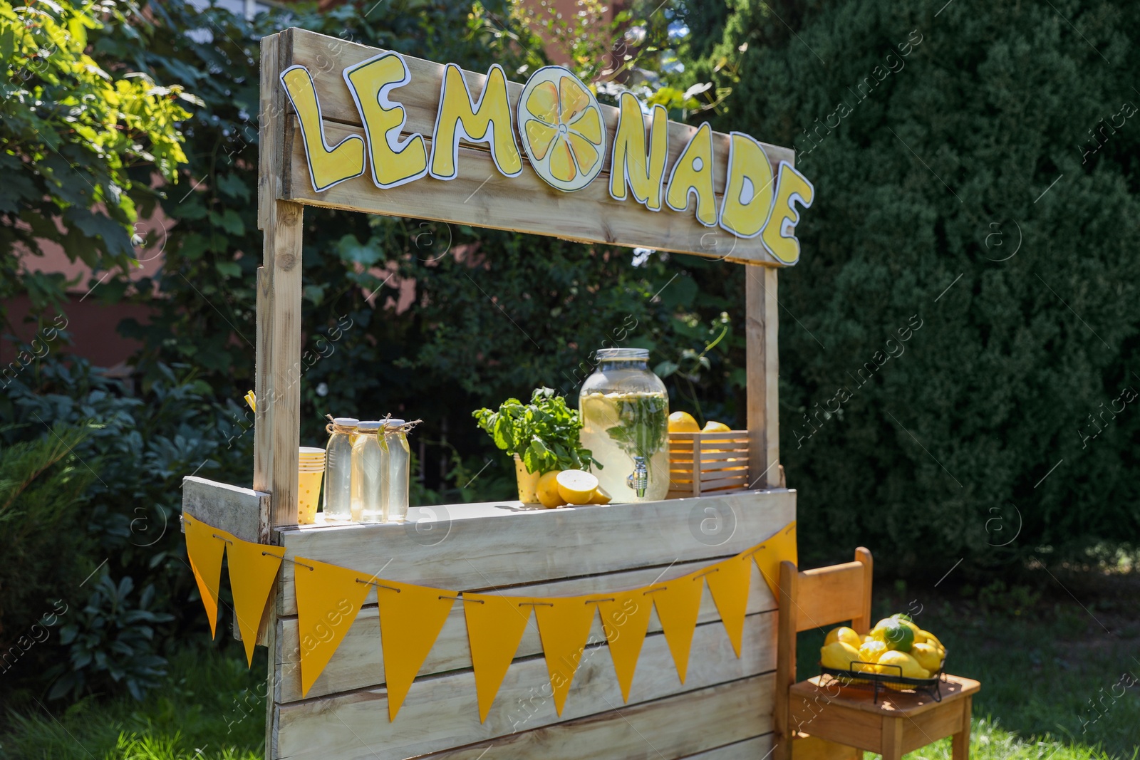 Photo of Lemonade stand with refreshing drink, fruits and mint in park