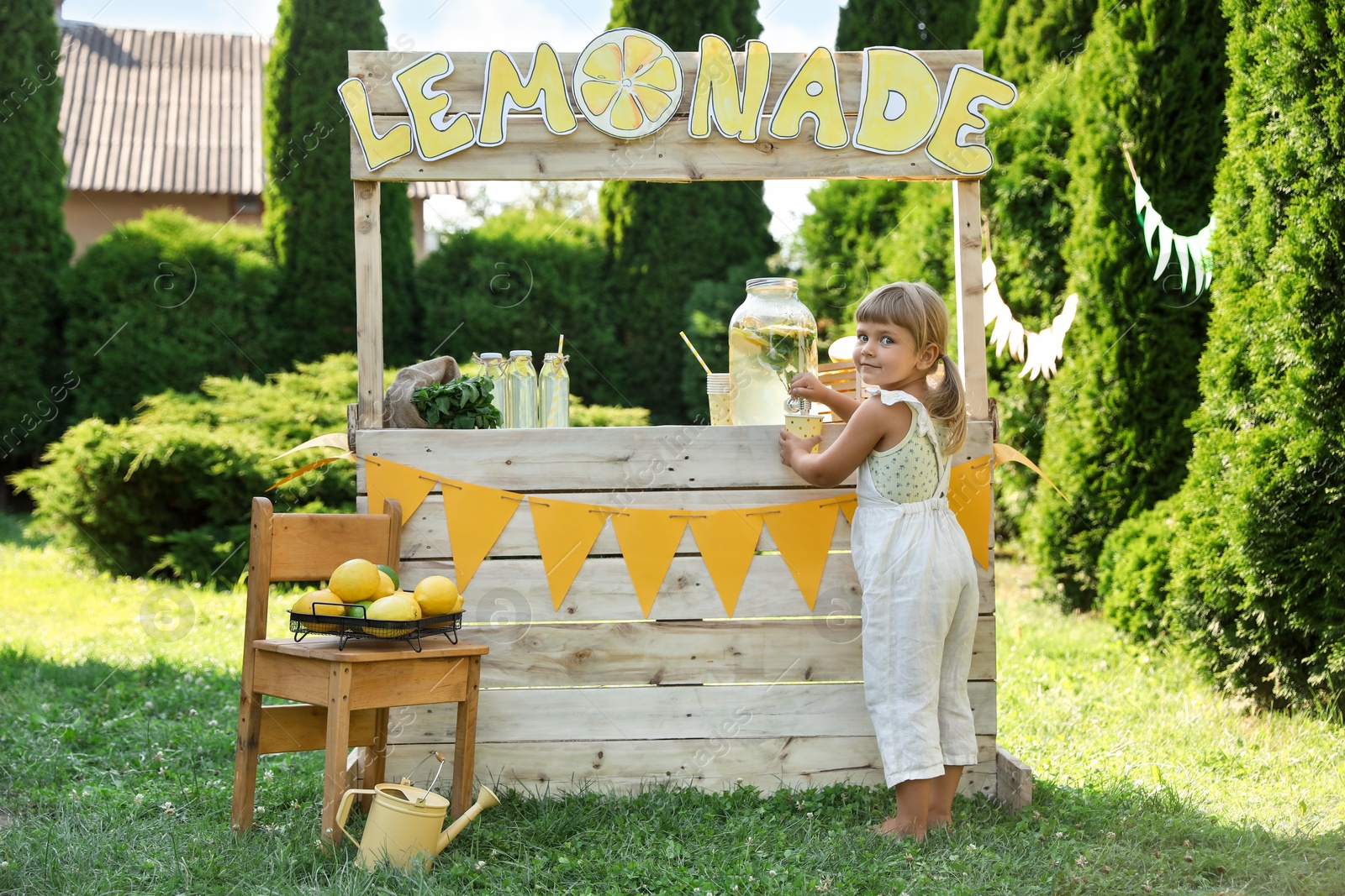 Photo of Little girl pouring natural lemonade into paper cup in park