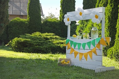 Lemonade stand with refreshing drink and fresh fruits in park, space for text