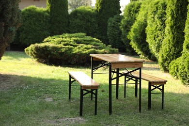 Photo of Wooden table with benches in garden on sunny day