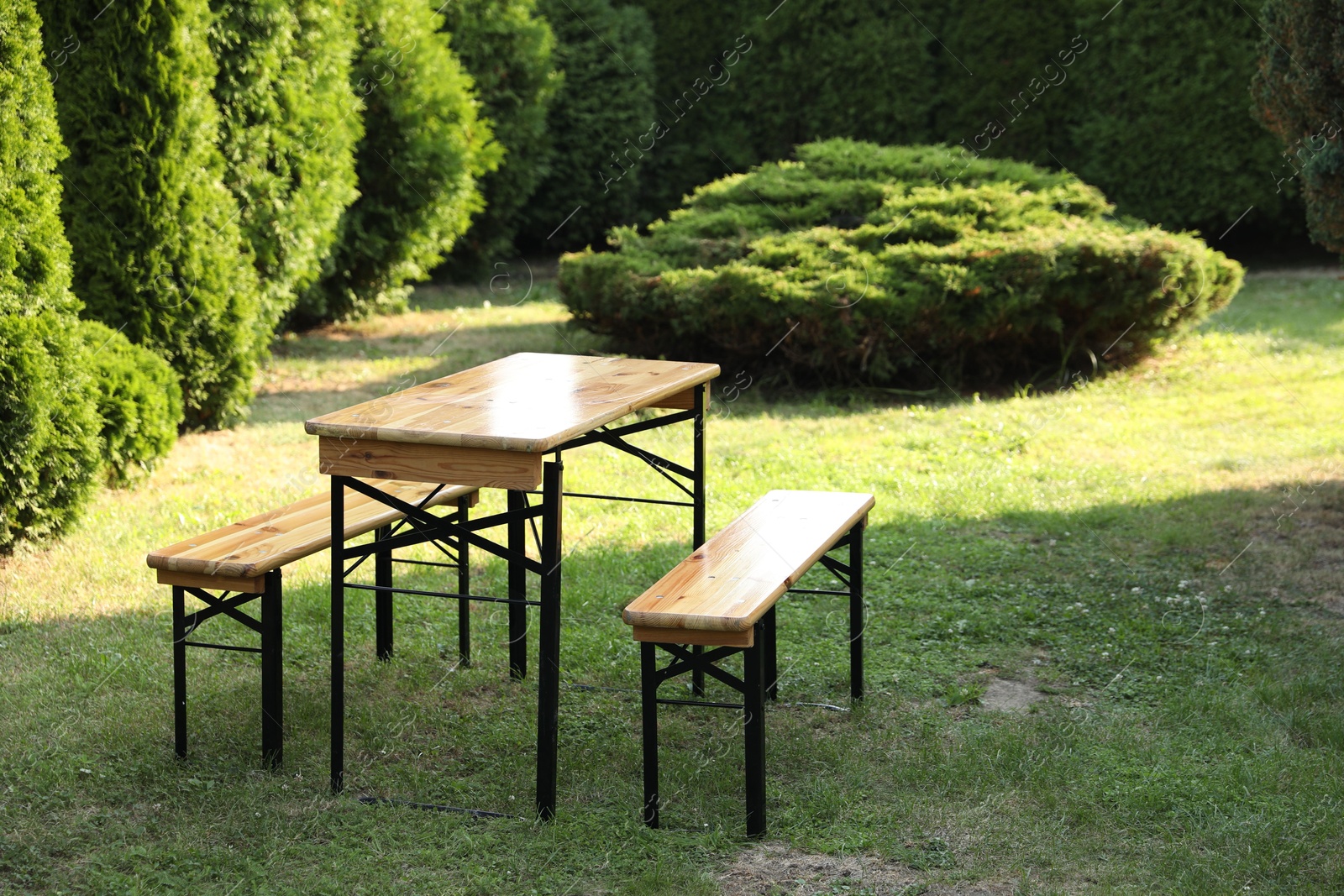 Photo of Wooden table with benches in garden on sunny day