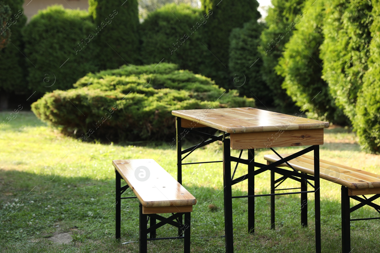 Photo of Wooden table with benches in garden on sunny day