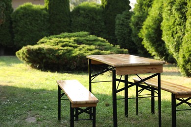 Photo of Wooden table with benches in garden on sunny day